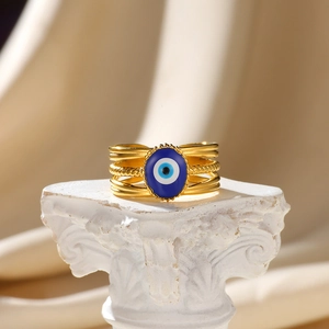 Macro detail of gold multi-layer evil eye ring on a satin background with elegant column