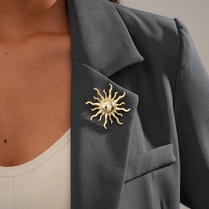 Close-up of golden sun-shaped brooch on a dark grey suit lapel for business style
