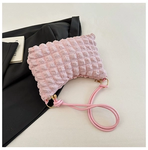 Detail of pink bubble textured shoulder bag on black blazer with golden metal hooks