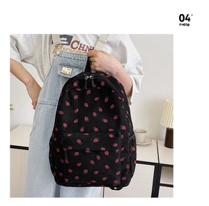 Detail shot of black corduroy backpack with strawberry pattern worn by a model