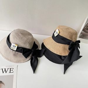 Dettaglio cappello da sole in lino a tesa larga con grande fiocco di nastro nero decorativo
