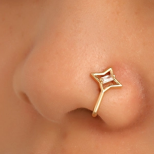 Detailed shot of a gold star-shaped non-piercing nose cuff with a clear zircon stone