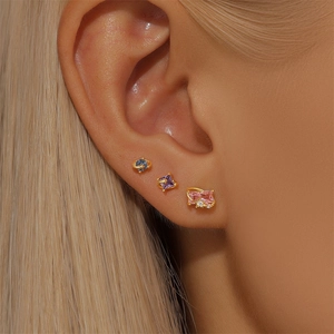 Macro shot of gold S925 silver stud earrings with blue, purple, and pink gemstones