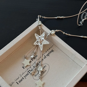 Detail of bohemian star pendant necklace with beige braided cord on a textured display tray