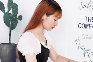 Détail de boucles d'oreilles dorées à glands portées par un mannequin en robe
