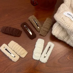 Detailed view of plush knit fabric hair clips in warm autumn colors on a wooden surface