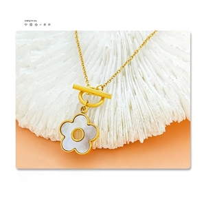 Detail of 18K gold plated titanium necklace with shell flower pendant and OT toggle clasp