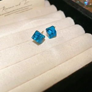 Gros plan de boucles d'oreilles clous en cristal bleu menthe sur support en velours