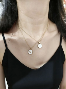 Dettaglio di collane dorate a strati con ciondoli a cuore bianco sul collo della modella