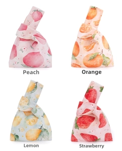 Flat lay of four Japanese fruit print knot bags in peach, orange, lemon and strawberry