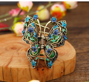 Detail of vintage bronze butterfly hair claw with blue flowers and green enamel