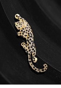 Macro shot of gold leopard brooch with white rhinestones and green emerald eyes