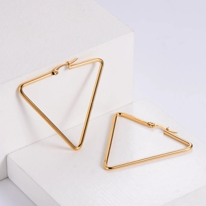 Minimalist gold titanium steel triangle hoop earrings on white geometric stands