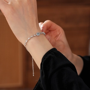 Close-up of a silver zircon flower bracelet with a blue gemstone on a woman's wrist