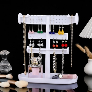 White multi-layer jewelry stand with earring holes, hooks and tray on black background