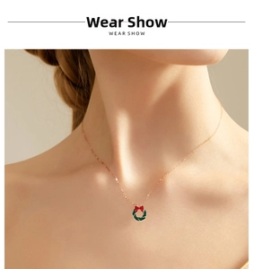 Close-up of a festive Christmas wreath pendant necklace with a red bow on a model