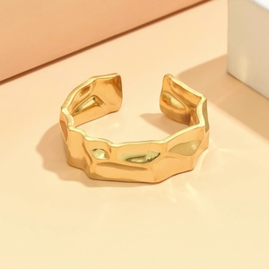 Minimalist gold stainless steel open bangle with irregular hammered texture on geometric background