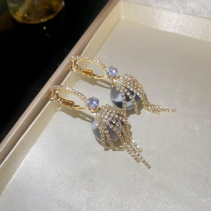 Detailed close-up of golden tassel earrings with sparkling cubic zirconia and marble beads