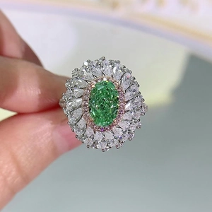 Detailed close-up of a silver ring with an oval green gem and pear-shaped petal diamonds