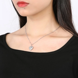 Detail of silver heart leaf texture pendant necklace worn by a model against black clothing