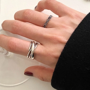 Close-up of 925 sterling silver woven ring and vintage geometric hollow band on hand