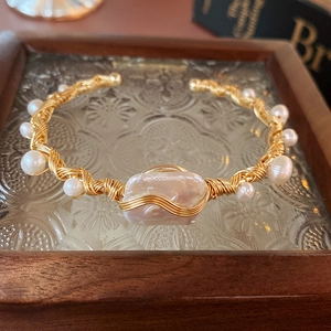 Detail of handmade wire-wrapped gold bracelet with baroque pearls and textured finish