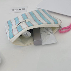 Detail view of striped canvas bag used for cosmetics with blue stripes and pink handles