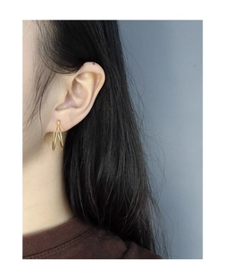 Detail view of a model wearing double-layered golden U-shape hoop earrings in S925 silver