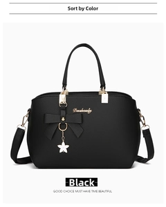 Close-up of black pebble leather handbag featuring a leather bow and star metal pendant