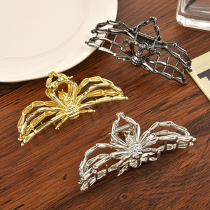 Three-color metal spider hair claws in gold, silver, and black on a wooden table