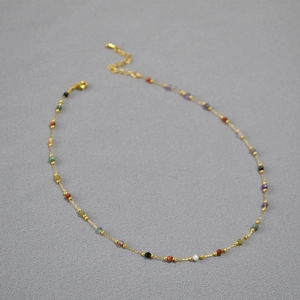 Detail of delicate gold chain necklace with colorful natural stones and lobster clasp
