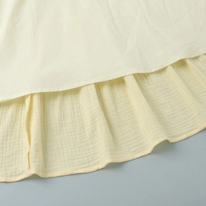 Detailed close-up of light yellow tiered cake skirt with ruffles and cotton texture