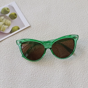 Detail of green cat-eye sunglasses with metal rivets on textured white background
