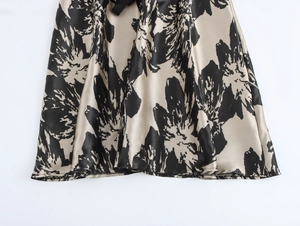 Detail of elegant satin maxi dress hem with black floral patterns on beige silk fabric