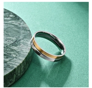 Detail of two-tone stainless steel ring with gold band on green marble surface