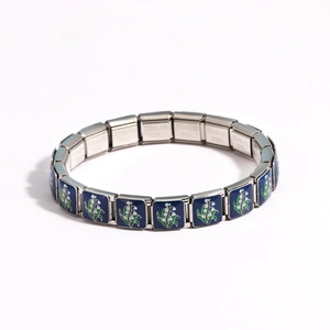 Close-up of stainless steel modular link bracelet with blue enamel lily flower pattern