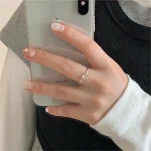 Close-up of minimalist silver heart-shaped open ring worn on a finger