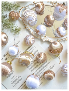 Detailaufnahme champagnerfarbener Satin-Weihnachtskugeln mit Pailletten auf einem Vintage-Tablett
