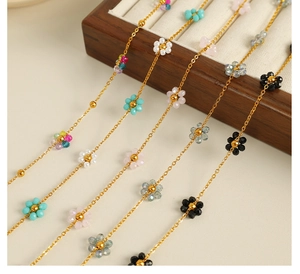 Close-up of colorful beaded flower necklaces in various colors with gold metal chains