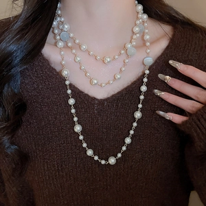 Détail d'un collier de perles multicouche de style français sur un pull marron