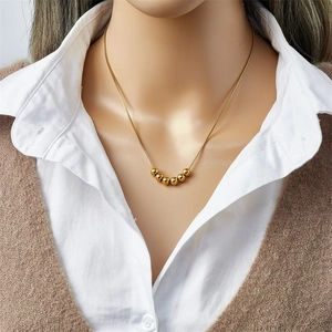 Golden titanium steel beaded chain necklace on model with elegant minimalist design