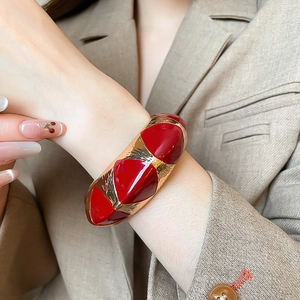 Detailed macro view of retro wide geometric bangle with red enamel and gold metal textures