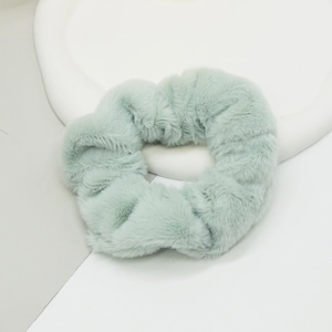 Détail d'un chouchou en fausse fourrure vert clair montrant sa texture douce et ses fibres