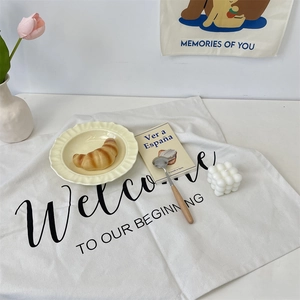 Close-up of white cotton linen placemat with Welcome to our beginning print for home decor