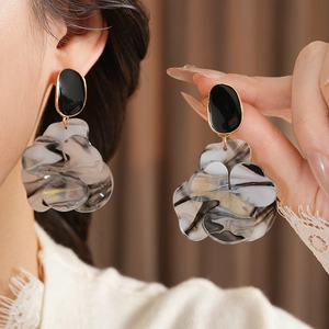 Detailed view of large marble resin flower earrings with gold accents and black studs