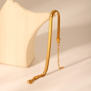 Detailed close-up of 18k gold snake chain bracelet with lobster clasp and texture
