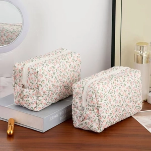 Detail of floral quilted cotton makeup bag with heart-shaped zipper puller on wooden desk