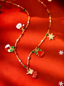 Detail of Christmas necklace with colorful enamel charms like Santa and bells on gold chain