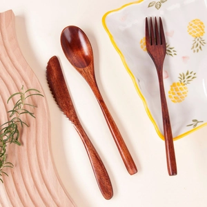 Close-up of nanmu wood cutlery set featuring wooden knife spoon and fork on a rustic table