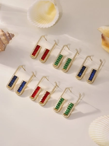 Macro shot of rectangular gold earrings with emerald, ruby, and sapphire zircons
